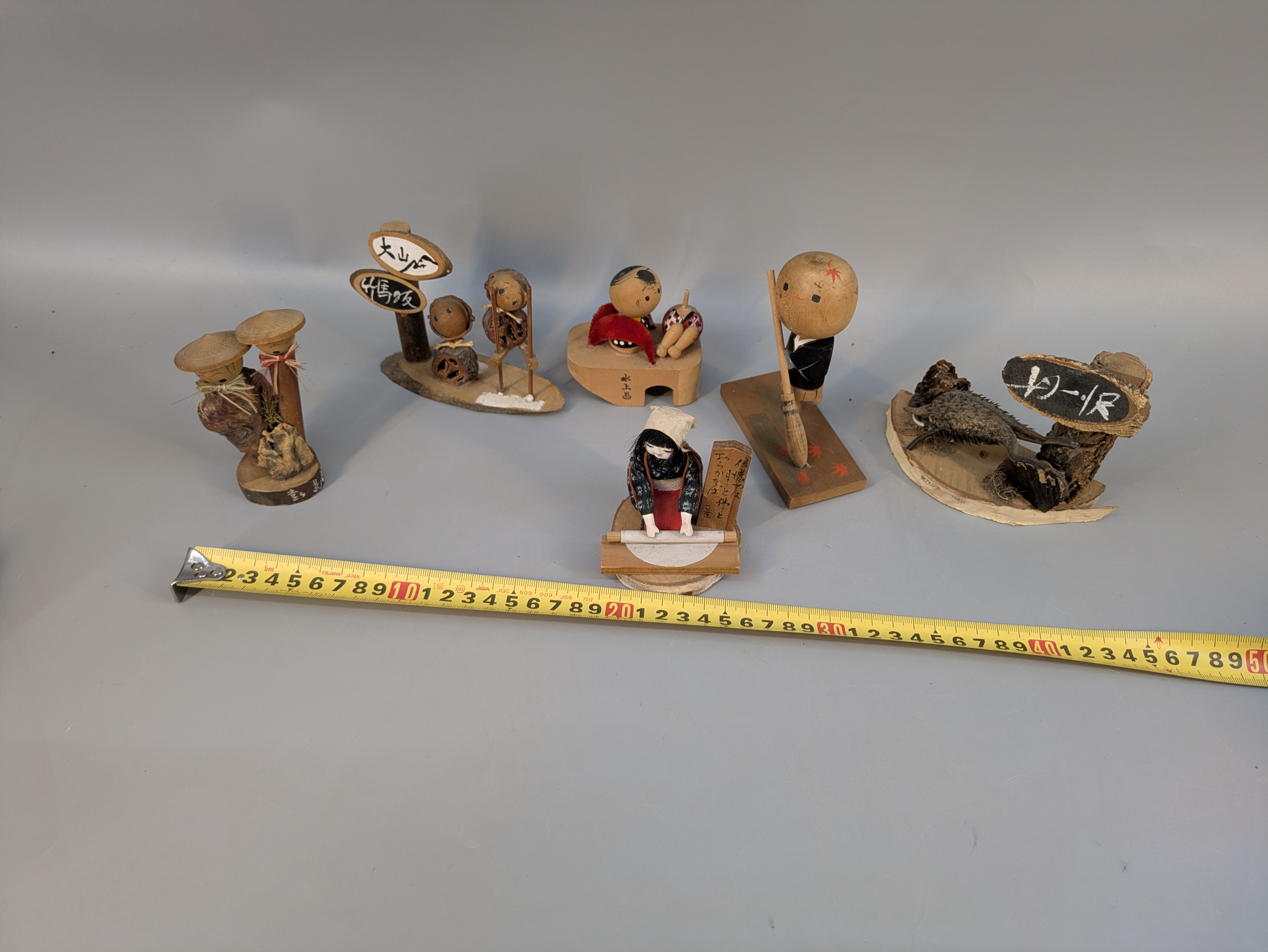 Miniature village figures shown with a ruler for scale