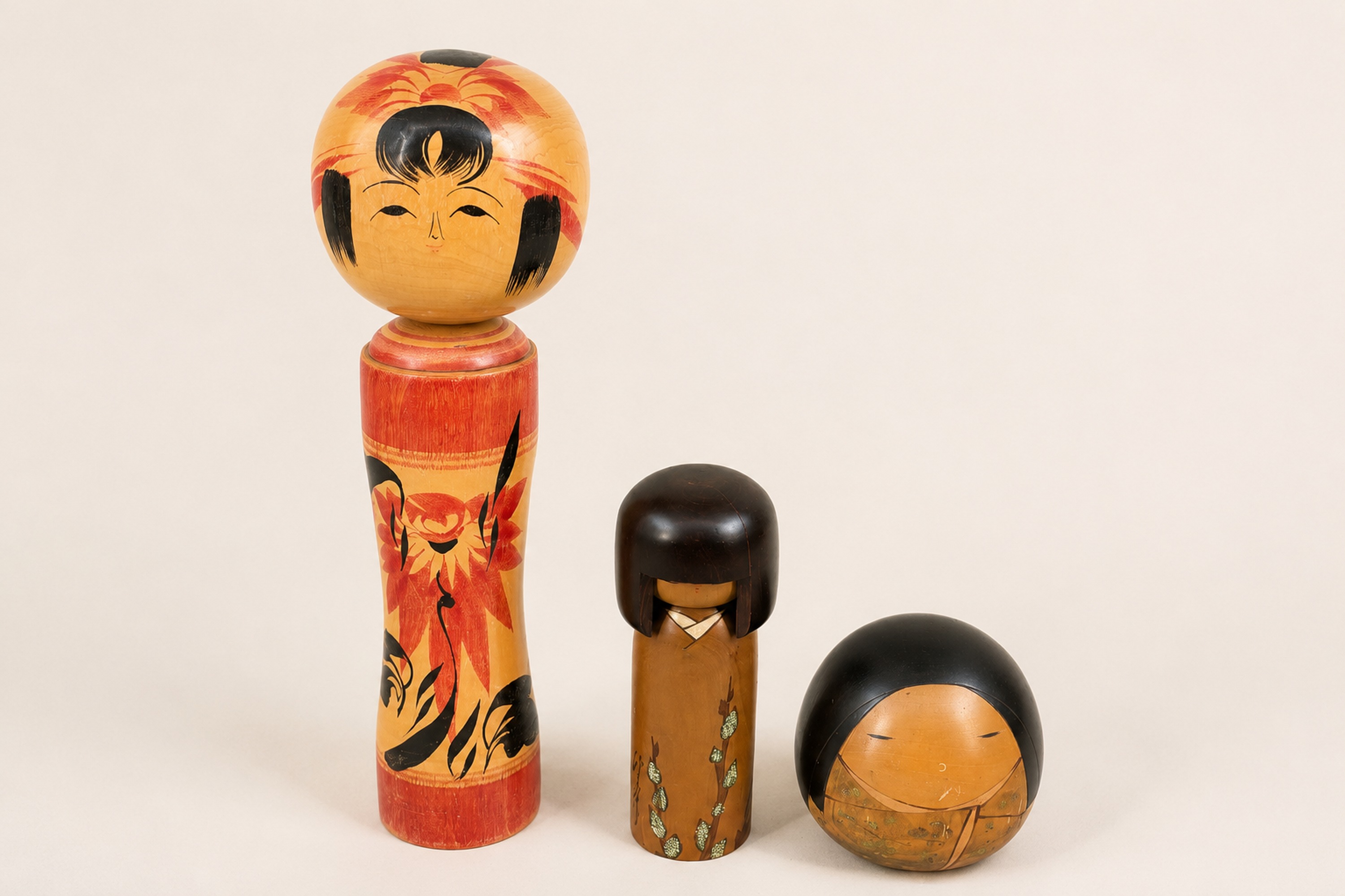 Three Japanese painted wooden kokeshi style dolls arranged as a set